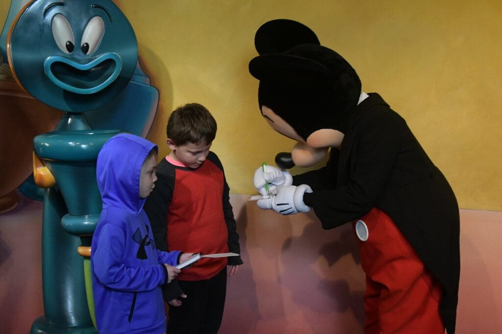 Boys meeting Mickey and getting in autograph in his house.